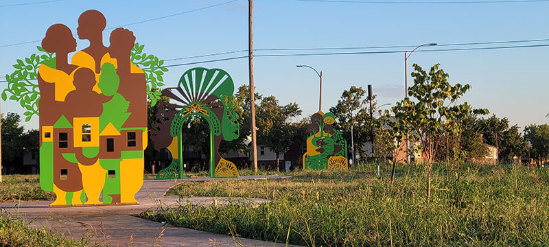 Enduring currents, a three-piece flat metal sculpture with Black figures and trees that are yellow, green and brown.