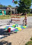 Artist Jamie Bonfiglio working on a crosswalk with stained-glass-like color blocks that are purple, yellow and green