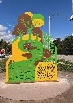 One part of a three-piece flat metal sculpture. This section has yellow, green and brown trees and water.