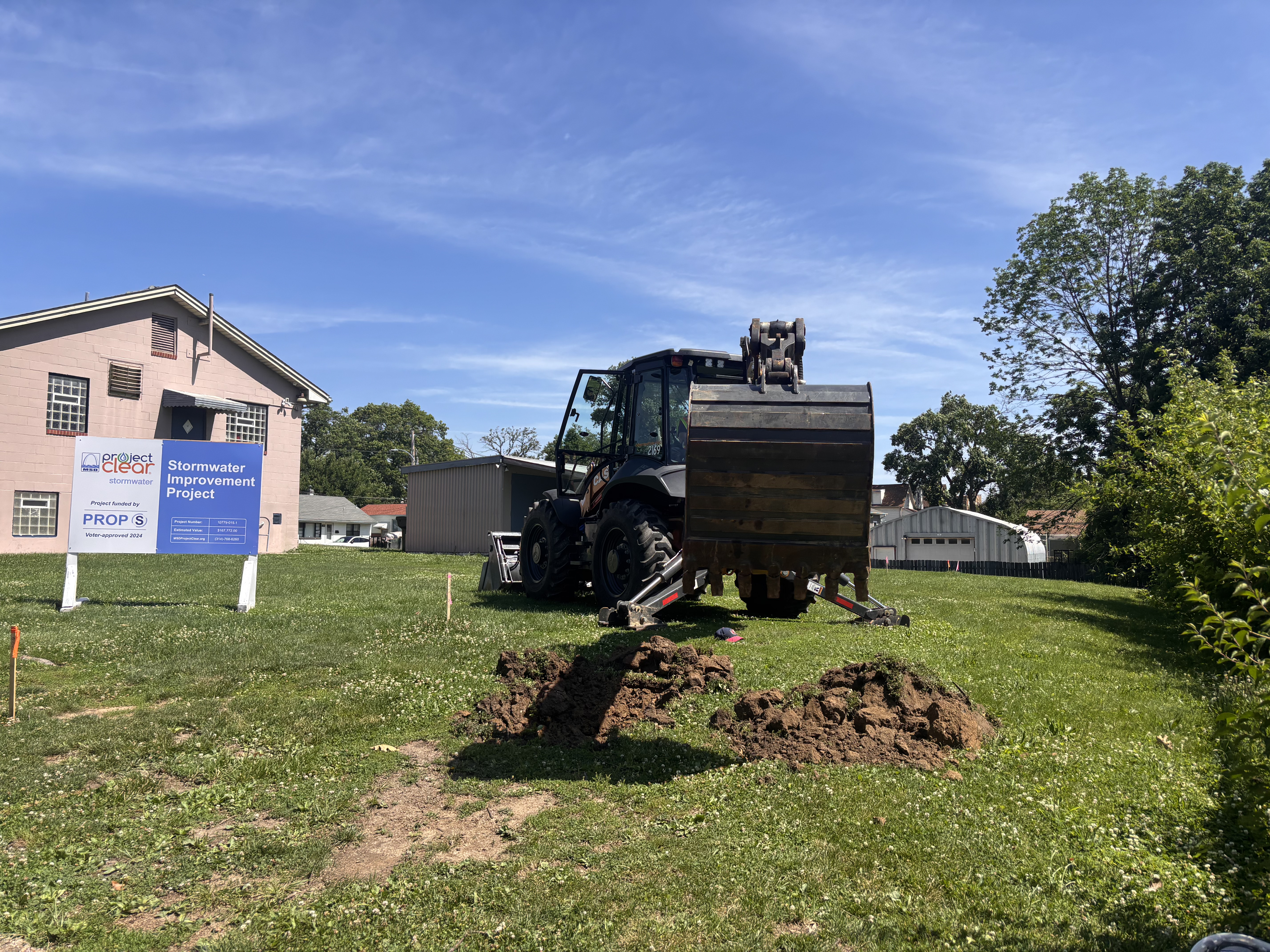 An excavator officially breaks the soil in the ceremonial ground breaking. 