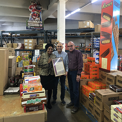 License collector Mavis Thompson poses with the two owners of General Candy Company