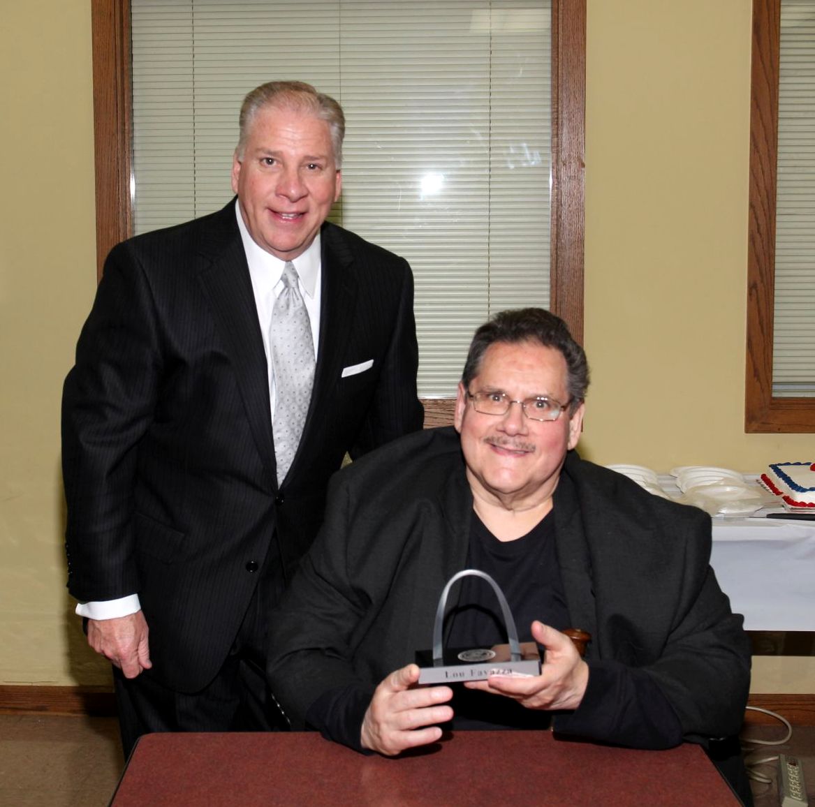 Collector of Revenue Gregory F.X. Daly presents Lou Favazza with an engraved Gateway Arch paperweight.